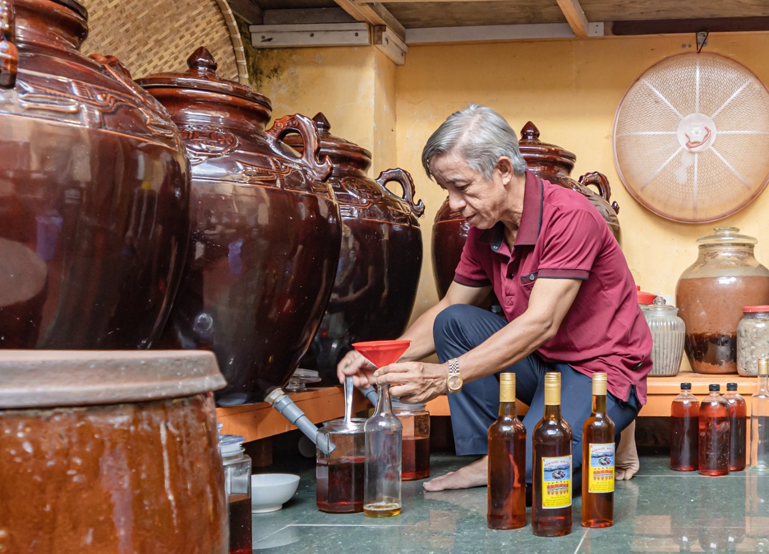 Ông Huỳnh Văn Mười, người làm mắm từ năm 17 tuổi nổi tiếng vùng Mân Thái đang chiết mắm Nhỉ ra chai.